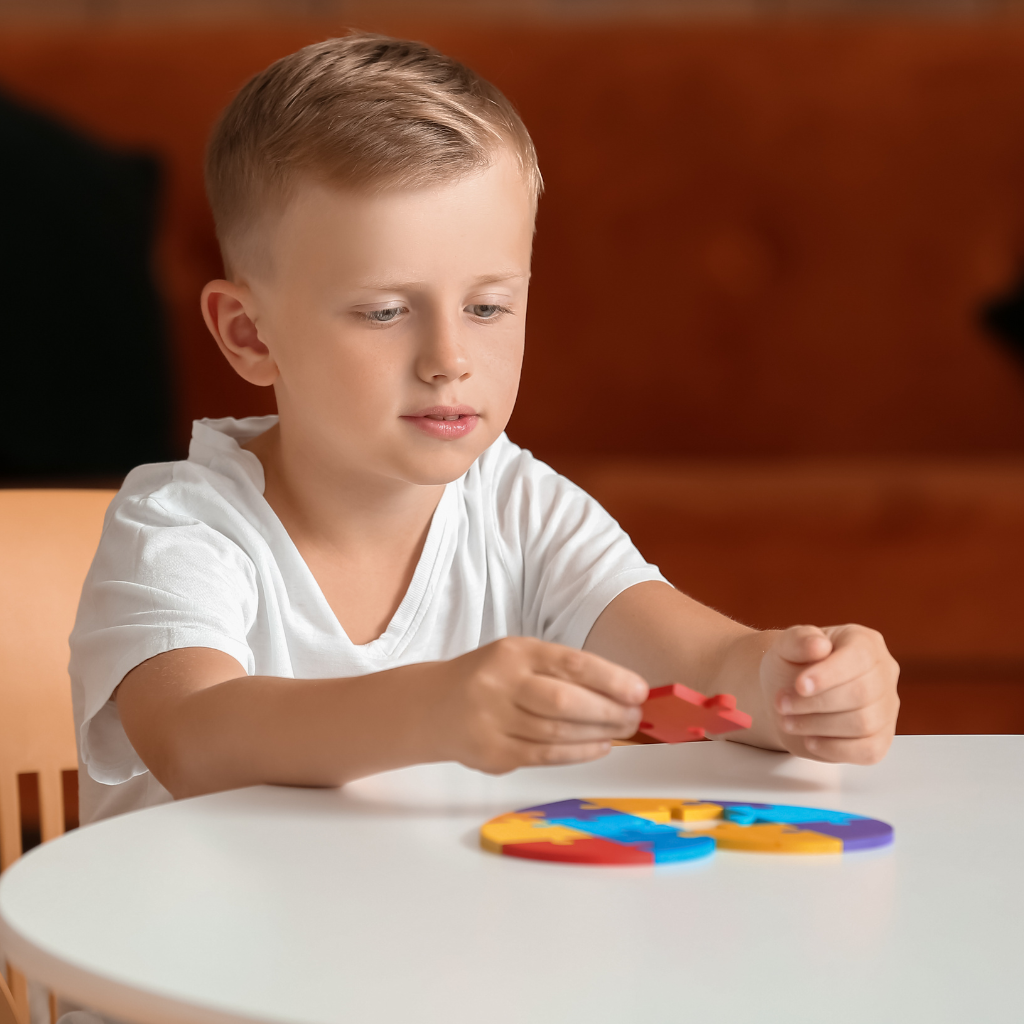 petit garçon jouant avec des pièces de puzzle coloré